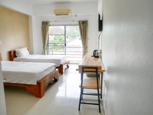 een kamer met 2 bedden, een bureau en een raam bij Fang Villa Hotel in Fang