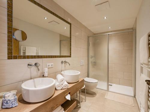 a bathroom with two sinks and a toilet and a mirror at Hotel Feichter in Söll
