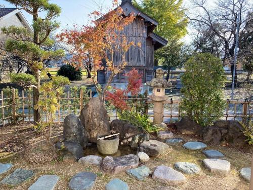 a garden with a fountain in front of a wooden house at 小舞庵 Komaian in Tokushima