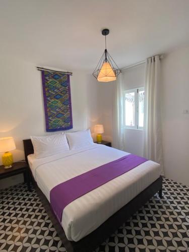 a bedroom with a large bed with purple and white sheets at Fides Boutique Hotel in Luang Prabang