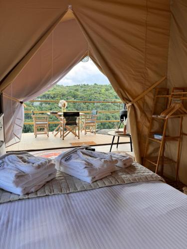 Tsivarás的住宿－Civara Chalet - Private Glamping in nature with Jakuzzi，一张位于帐篷内的床位,享有桌子的景色