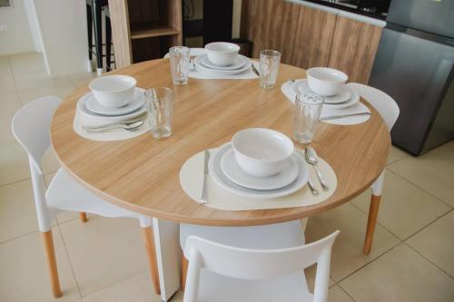 a wooden table with white plates and dishes on it at Spacious 3 Bedroom Appartement @Avida Allgauers in Iloilo City