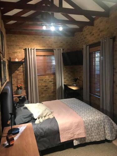 a bedroom with a bed and a desk and windows at Kyasaja Home away from home in Pretoria