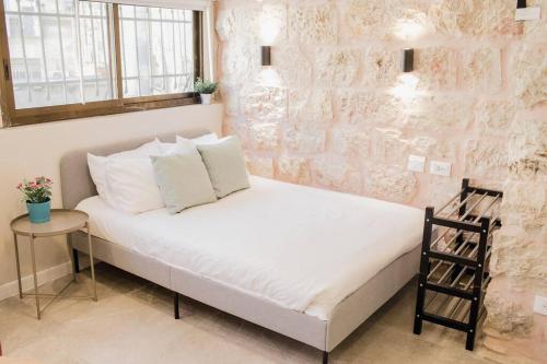 a bed in a room with a brick wall at Gabriel Apartments - Stone Suits JEM City Center in Jerusalem