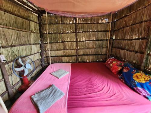 a small room with a pink bed and a fan at Sweet Jungle Glamping in Koh Rong Island