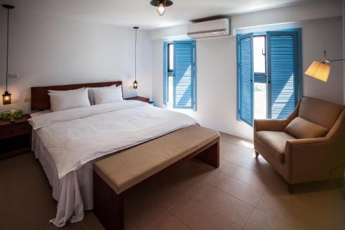 a bedroom with a bed and a chair and windows at Oasis Hotel in Magong