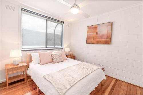 a white bedroom with a bed and a window at Orton Waves- Beach Life Awaits in Ocean Grove