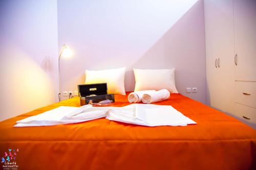 a bedroom with an orange bed with a laptop and towels at Liberte Maisonettes in Parga