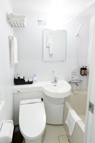 a white bathroom with a toilet and a sink at Ueno Woo Hotel in Tokyo