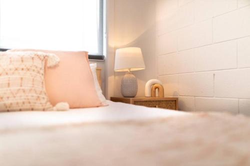 a bed with a pillow and a lamp on a table at Orton Waves- Beach Life Awaits in Ocean Grove