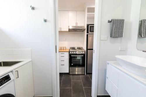 a white kitchen with a sink and a stove at Orton Waves- Beach Life Awaits in Ocean Grove
