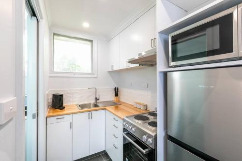 a kitchen with white cabinets and a stainless steel refrigerator at Orton Waves- Beach Life Awaits in Ocean Grove