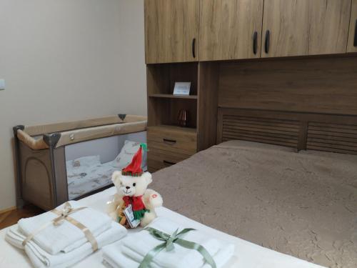 a teddy bear wearing a santa hat sitting on a bed at Apartman Centar in Požarevac