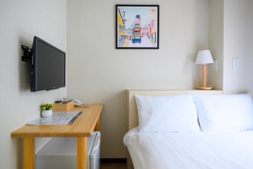 a bedroom with a bed and a desk with a television at Ueno Woo Hotel in Tokyo