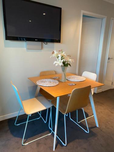 a wooden table with chairs and a vase of flowers on it at Saint Aubyn Retreat in New Plymouth