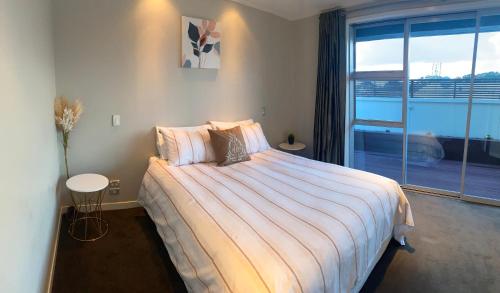 a bedroom with a large bed and a large window at Saint Aubyn Retreat in New Plymouth