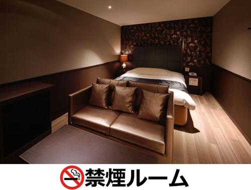 a bedroom with a bed and a leather couch at Hotel LALA - Kitashiga - (Adult Only) in Nagoya