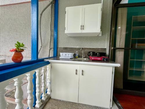 a kitchen with white cabinets and a sink at Ngermid Oasis - Studio W/ Kitchenette & Pool View in Koror