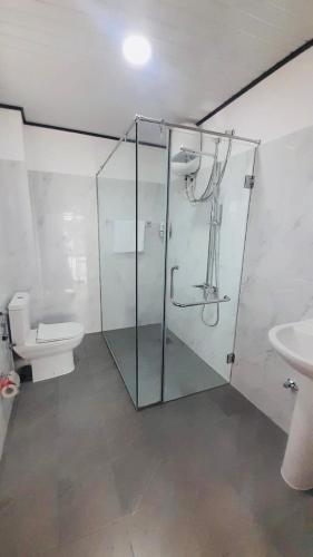 a bathroom with a glass shower and a toilet at Ivory Laze Hotel in Negombo