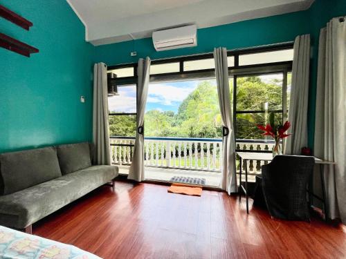 a living room with a couch and a large window at Ngermid Oasis - Studio W/ Kitchenette & Pool View in Koror
