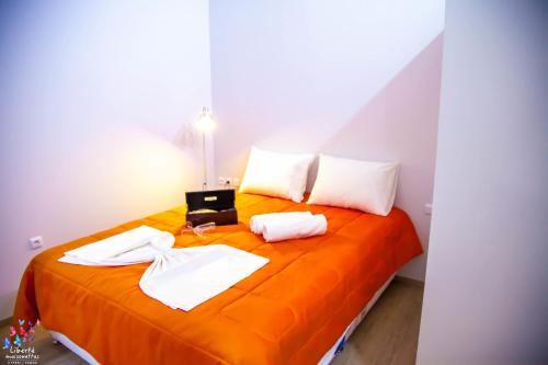 an orange bed with white sheets and a laptop on it at Liberte Maisonettes in Parga