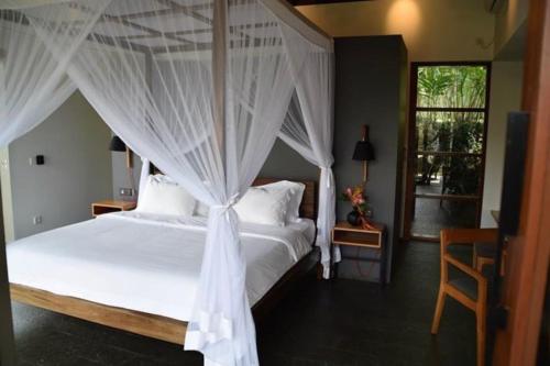 a bedroom with a white bed with a canopy at Bali River Retreat in Perean