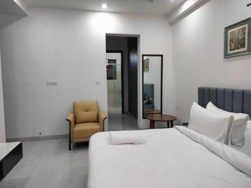 a bedroom with a white bed and a chair at The Hoften Elite 32 Avenue, Sector 15, Gurugram in Gurgaon