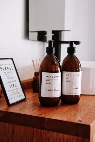 two bottles of soap sitting on a wooden shelf at Stanley Island in Plettenberg Bay
