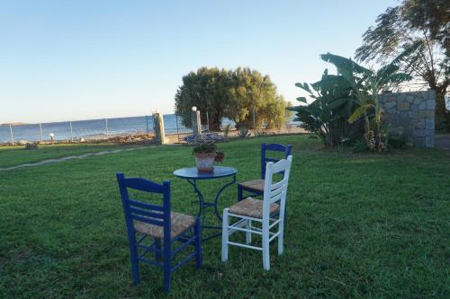 two chairs and a table in the grass near the ocean at Nicholas Waves Beach Studios in Lardos