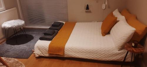 um quarto com uma cama grande e almofadas laranja em Alross studio flat / private bathroom em Londres