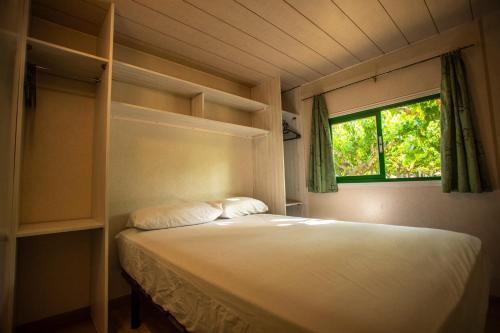 1 dormitorio con cama y ventana en Camping Clarà, en Torredembarra