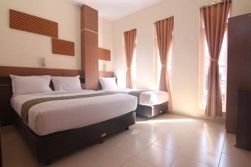 Habitación de hotel con 2 camas y 2 ventanas en Hotel Pules, en Yogyakarta