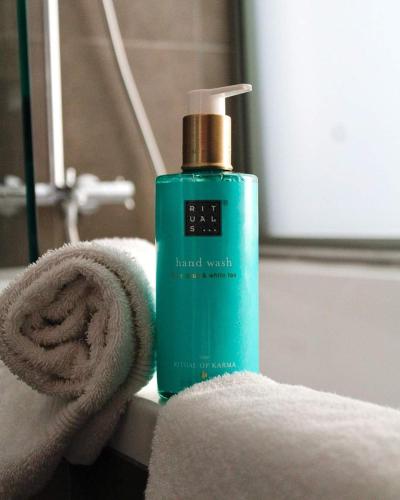 a green bottle of hand wash sitting next to a towel at Novotel Avignon Centre in Avignon