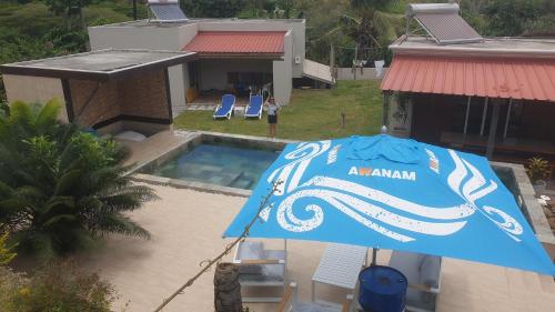 a blue umbrella in front of a house with a pool at Mangues Oasis in Rodrigues Island
