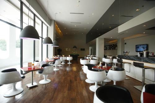 a restaurant with white chairs and tables and windows at Keys Select by Lemon Tree Hotels, Whitefield, Bengaluru in Bengaluru