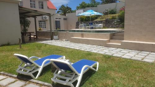 two lawn chairs sitting in the grass next to a house at Mangues Oasis in Rodrigues Island