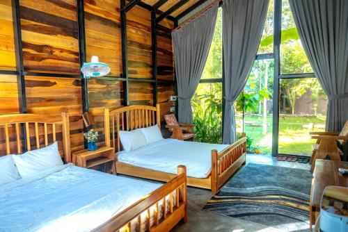 two beds in a room with wooden walls and windows at Tiên Sơn Pleiku Homestay in Pleiku