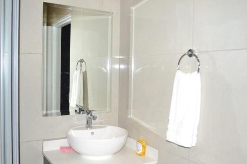 ein weißes Badezimmer mit einem Waschbecken und einem Spiegel in der Unterkunft Soldout Camp 1 in Johannesburg