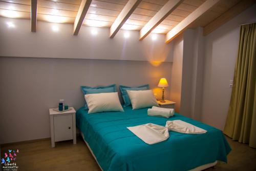 a bedroom with a bed with blue sheets and white pillows at Liberte Maisonettes in Parga