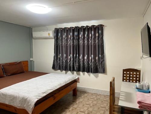 um quarto com uma cama e uma cortina preta em หอพักบ้านชูใจ em Phitsanulok