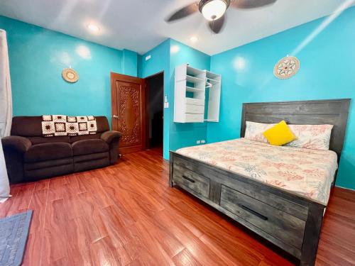 a bedroom with blue walls and a bed and a couch at Ngermid Oasis- 2 BD Master Suite in Koror