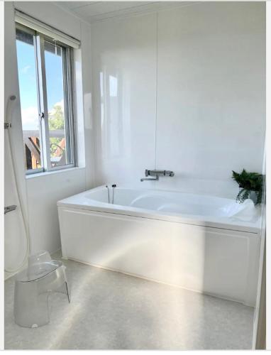 a white bathroom with a tub and a window at ハルク キャビン in Nakijin