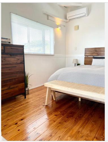 a bedroom with a bed and a dresser and a bench at ハルク キャビン in Nakijin
