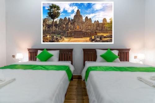 two beds in a room with a painting on the wall at The Khmer House Villas in Siem Reap