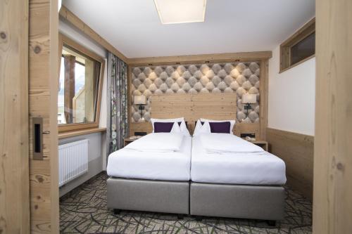 a bedroom with a large bed with white sheets and pillows at Hotel Pramstraller in Mayrhofen