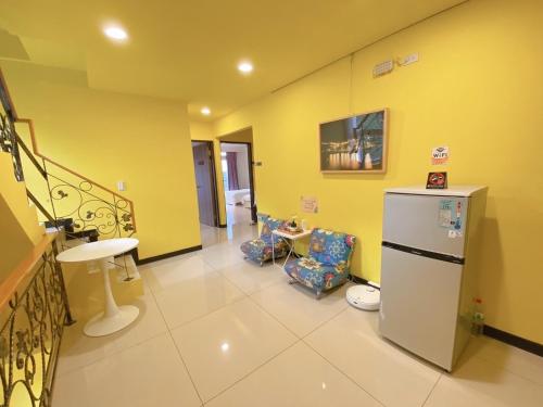 a room with yellow walls and a refrigerator and chairs at Bei Ao Bi Shan Jyu in Dongyin