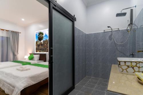 um quarto com uma cama e um chuveiro e uma casa de banho em The Khmer House Villas em Siem Reap