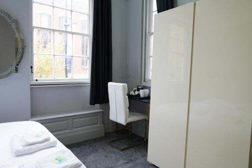 a bedroom with a bed and a desk and a window at Royal Hotel Kettering in Kettering