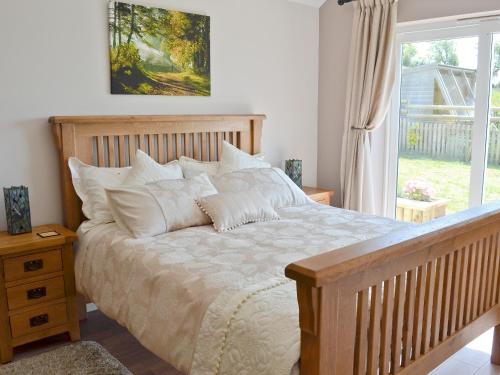 a bedroom with a large bed with white pillows at Beehive Cottage in Bodfari