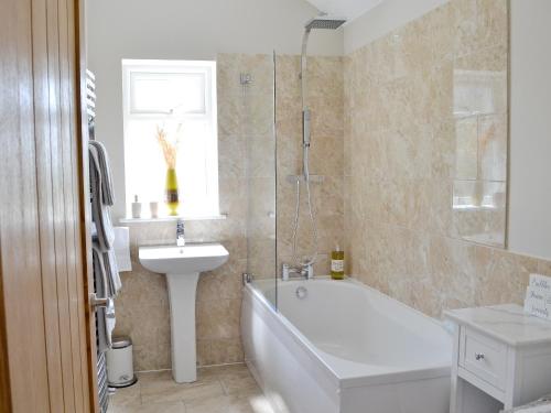 a bathroom with a bath tub and a sink and a bath tub at Beehive Cottage in Bodfari